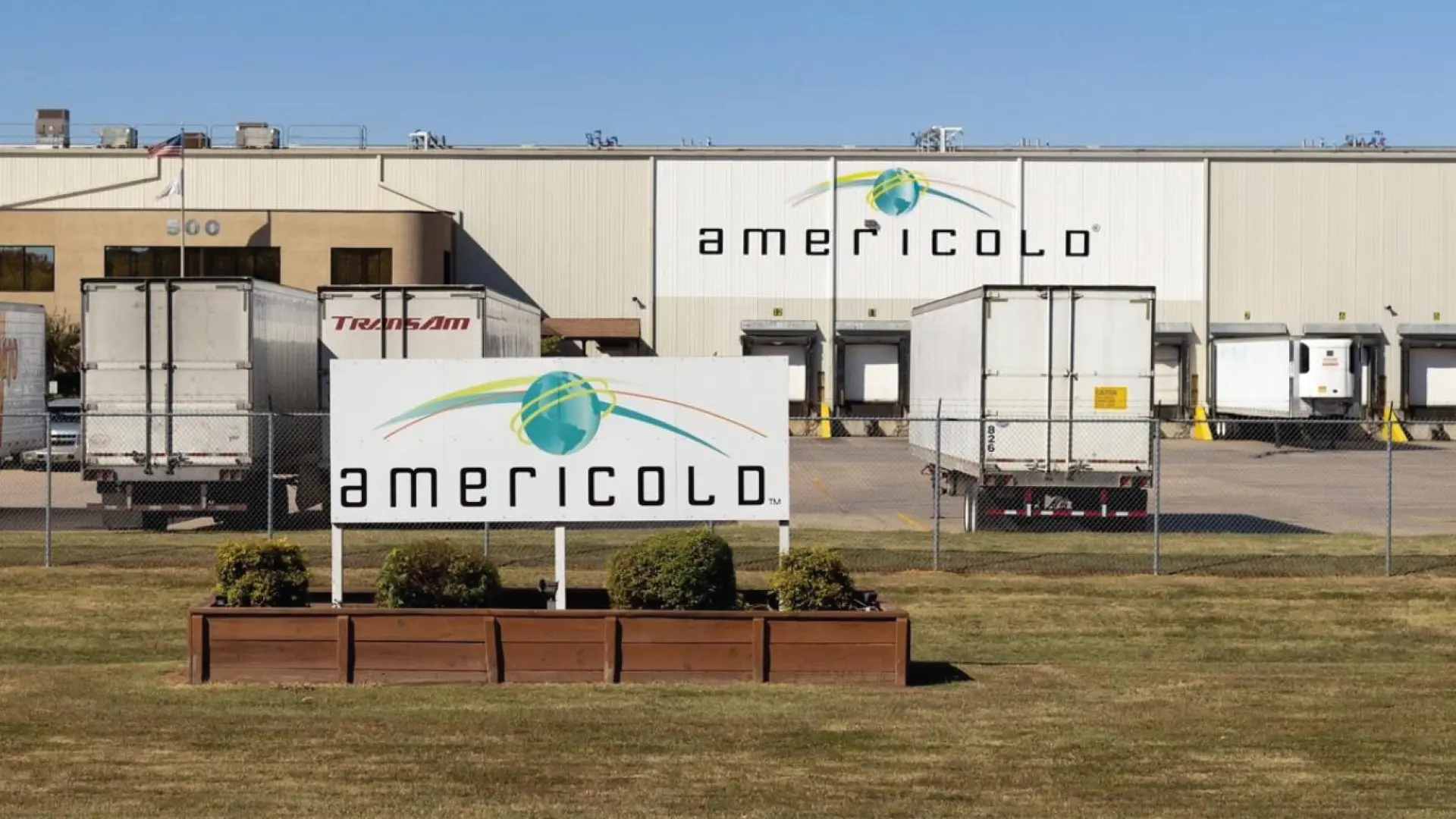 Americold facility with loading docks and trailers, showcasing the company’s role in temperature-controlled warehousing and logistics services