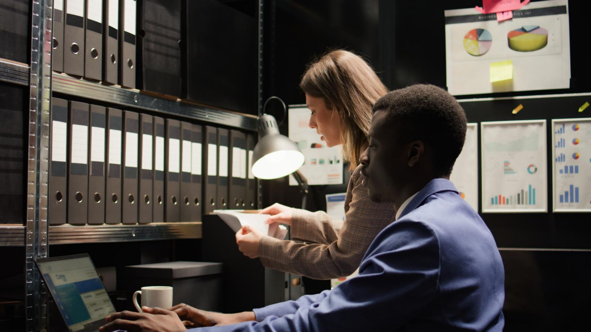 An image showing a law firm where one individual is working on a lalptop, searching data and another female individual is searching data from file folders, highlighting the importance of data retention for law firms.