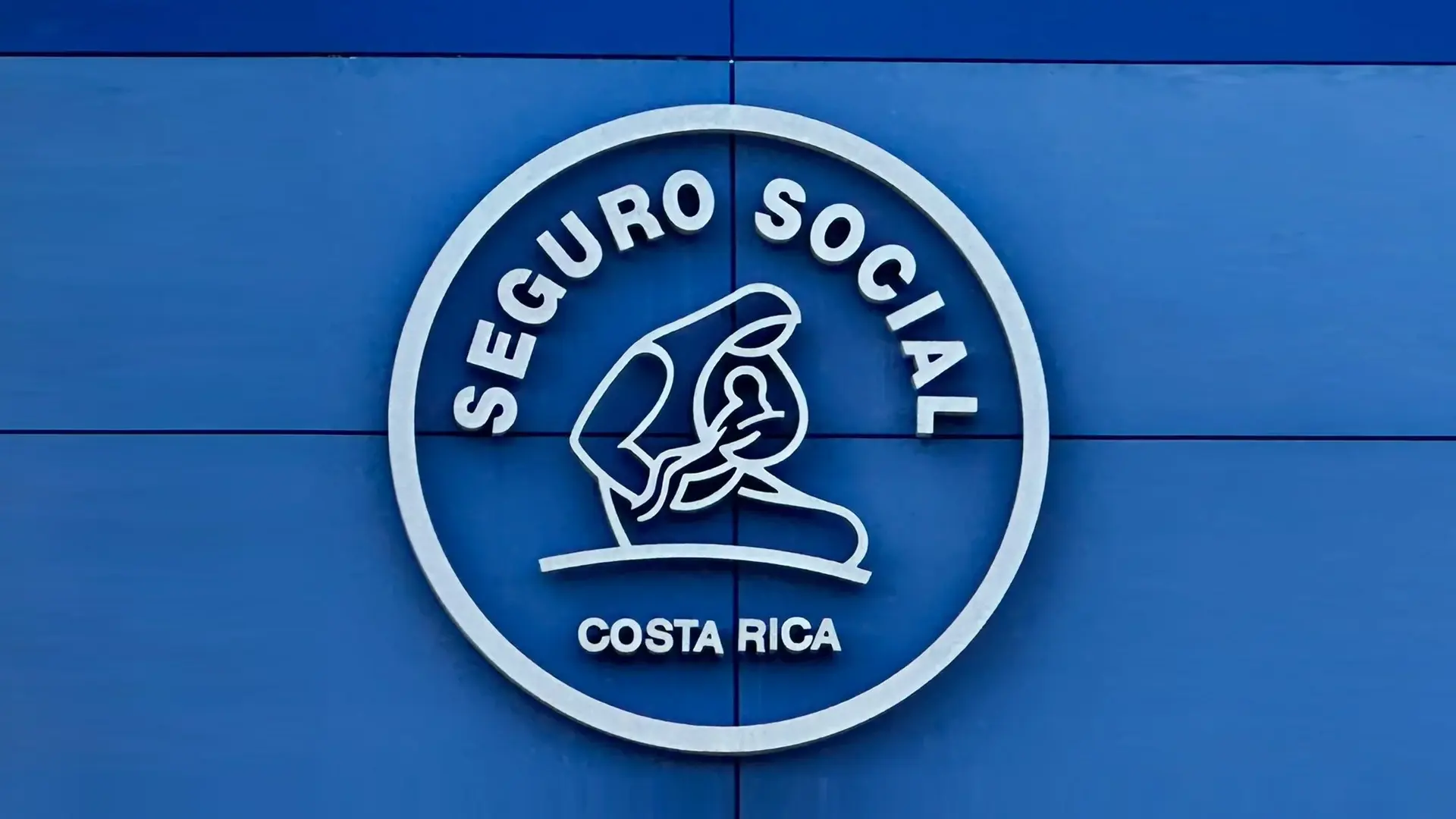 Logo of Costa Rica's Social Security Fund (CCSS) on a blue background, featuring the text 'Seguro Social Costa Rica' and a symbolic image of a caregiver holding a child