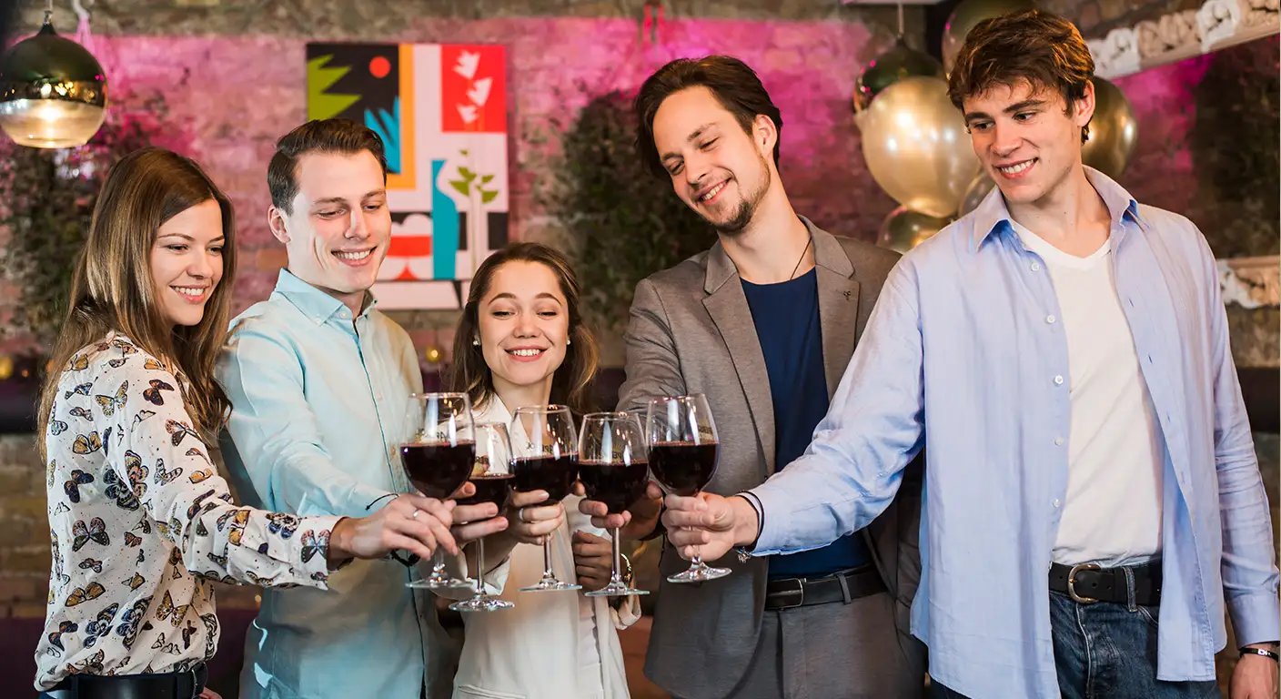 Group of Campari brand ambassadors celebrating with cocktails, surrounded by iconic Campari bottles, highlighting the brand’s vibrant spirit and commitment to mixology and social experiences