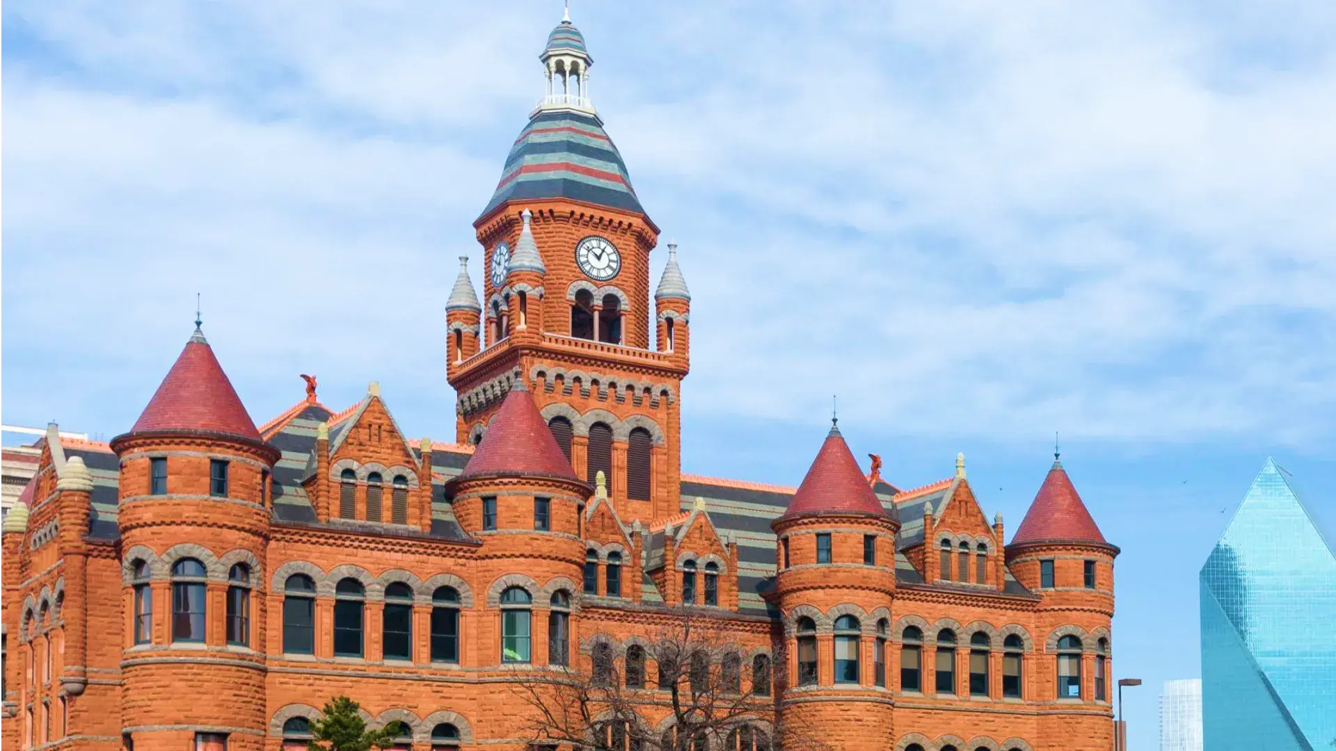 Historic red-brick courthouse with clock tower in Dallas County, Texas, showcasing Romanesque architecture against a clear sky