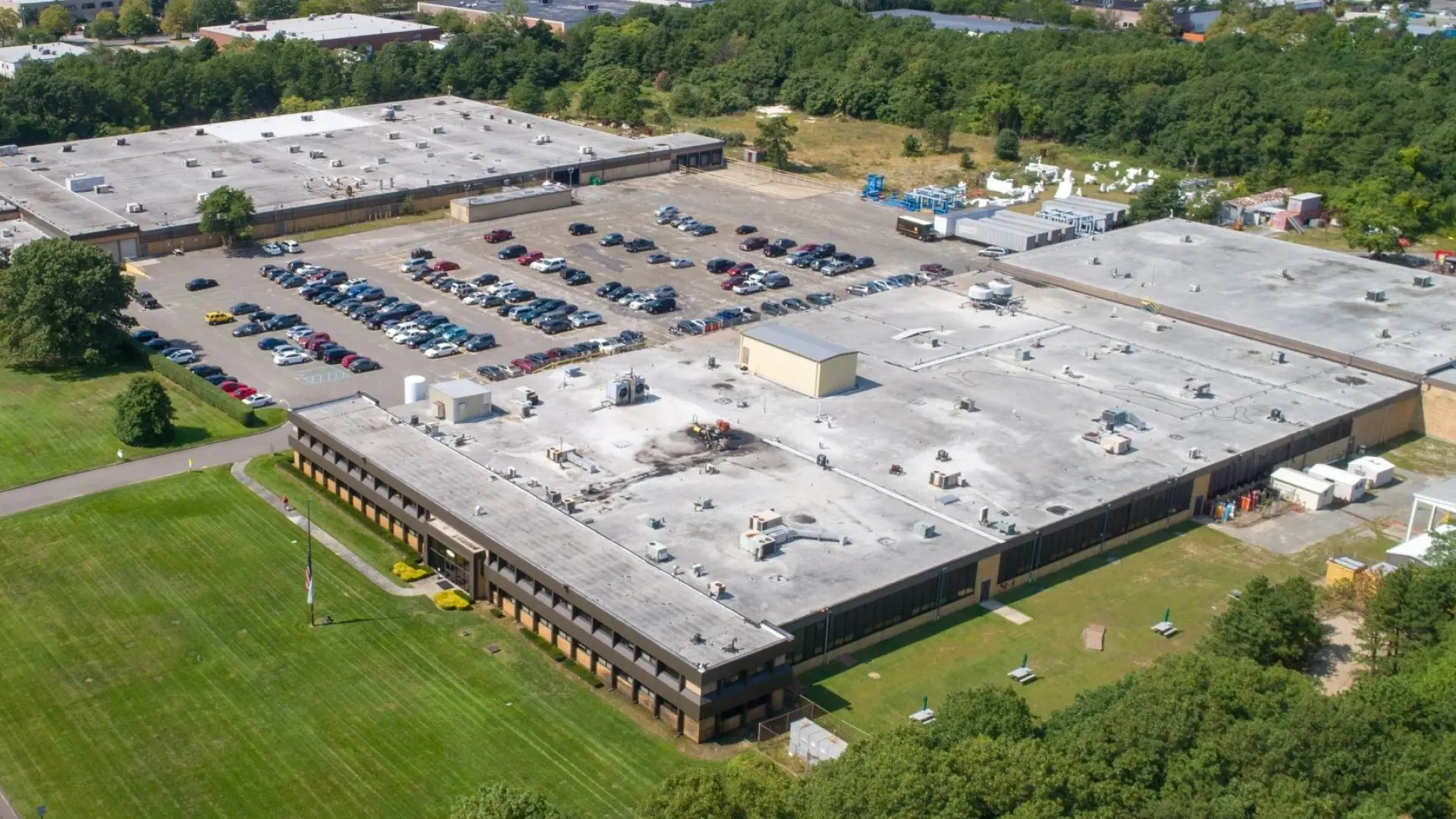 Aerial view of Dayton T. Brown, Inc. facility, showing large industrial buildings, parking lots, and surrounding green space, representing the company's expansive testing, engineering, and technical service operations