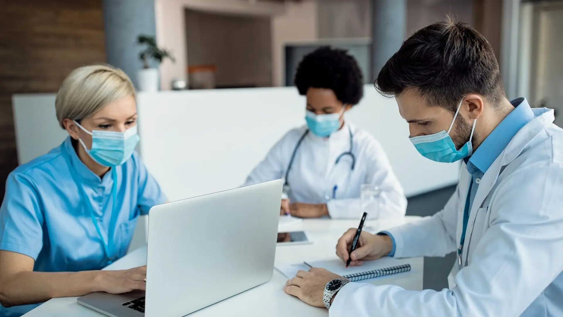 Healthcare professionals in masks collaborating at a desk, representing the team-based, patient-centered care approach at El Dorado Community Health Centers