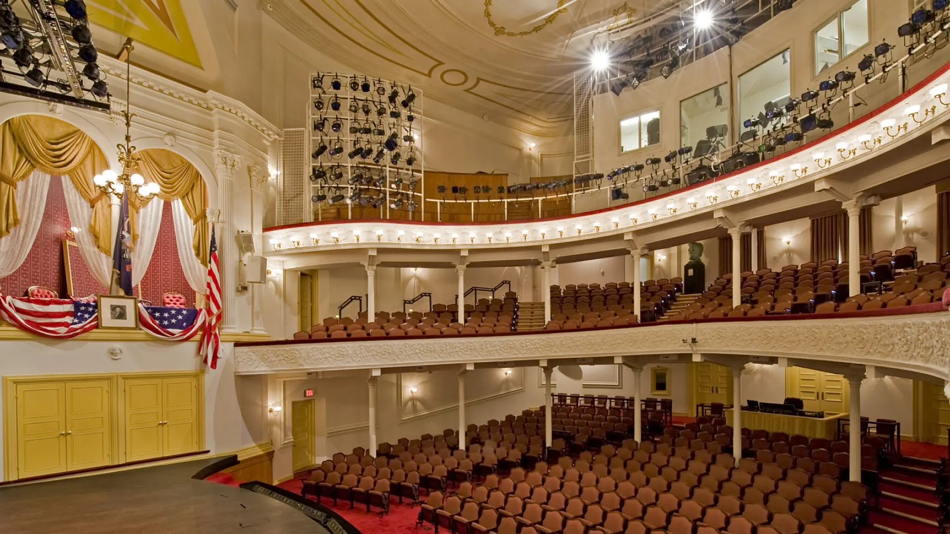 Interior of Ford's Theatre, showing the historic presidential box adorned with American flags, elegant balconies, and seating arrangements, highlighting the venue's architectural beauty and its significance in American history