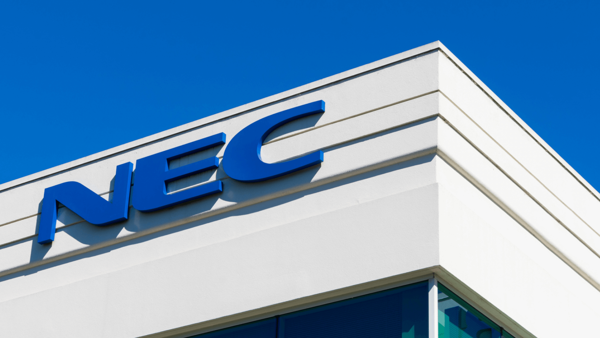  The NEC building logo on a modern white structure against a clear blue sky, representing NESIC's technology and communications services