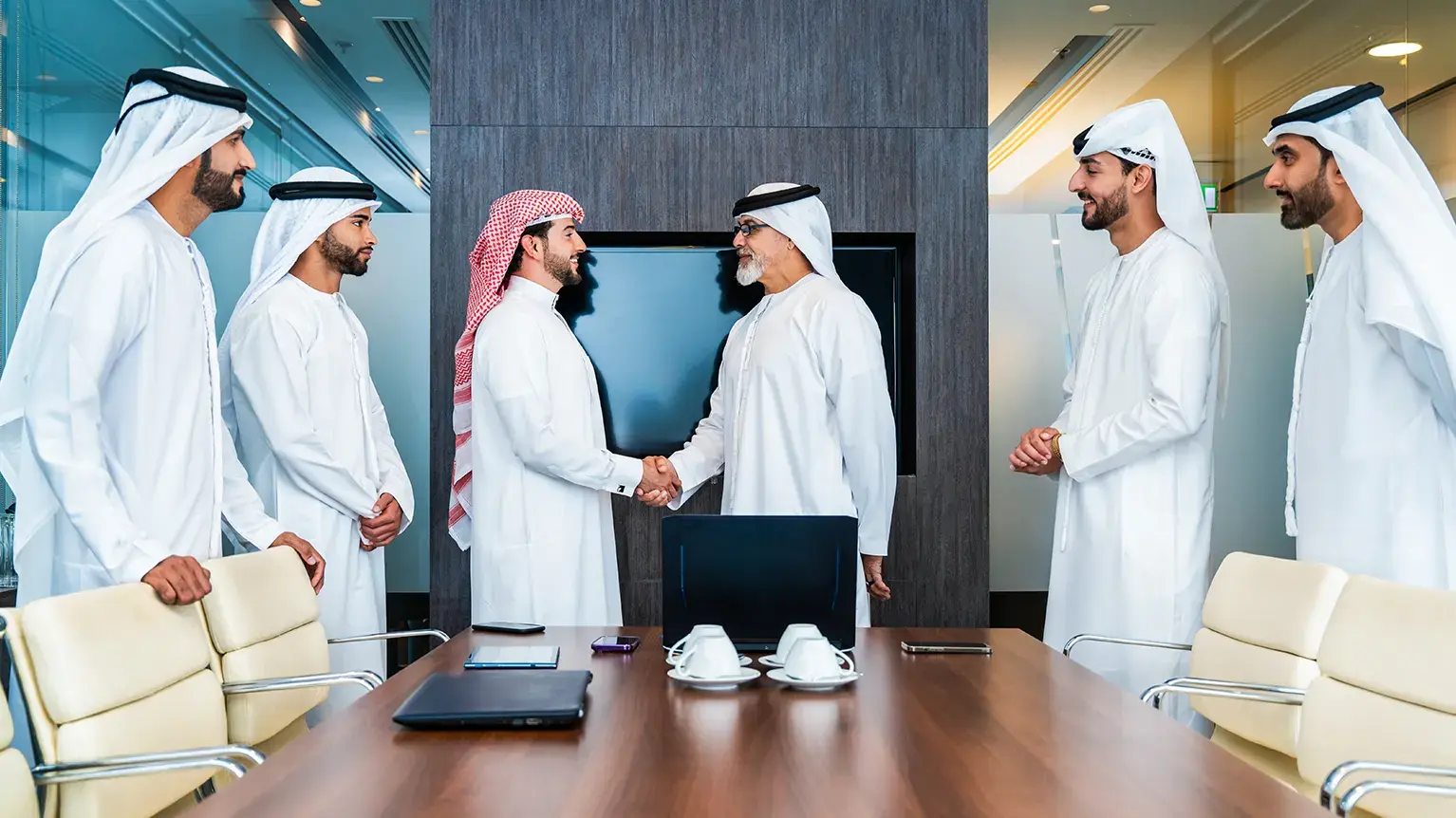 A group of executives, including Omani representatives in traditional attire, handshake with CEO, symbolizing a business meeting related to Oman LNG’s energy initiatives