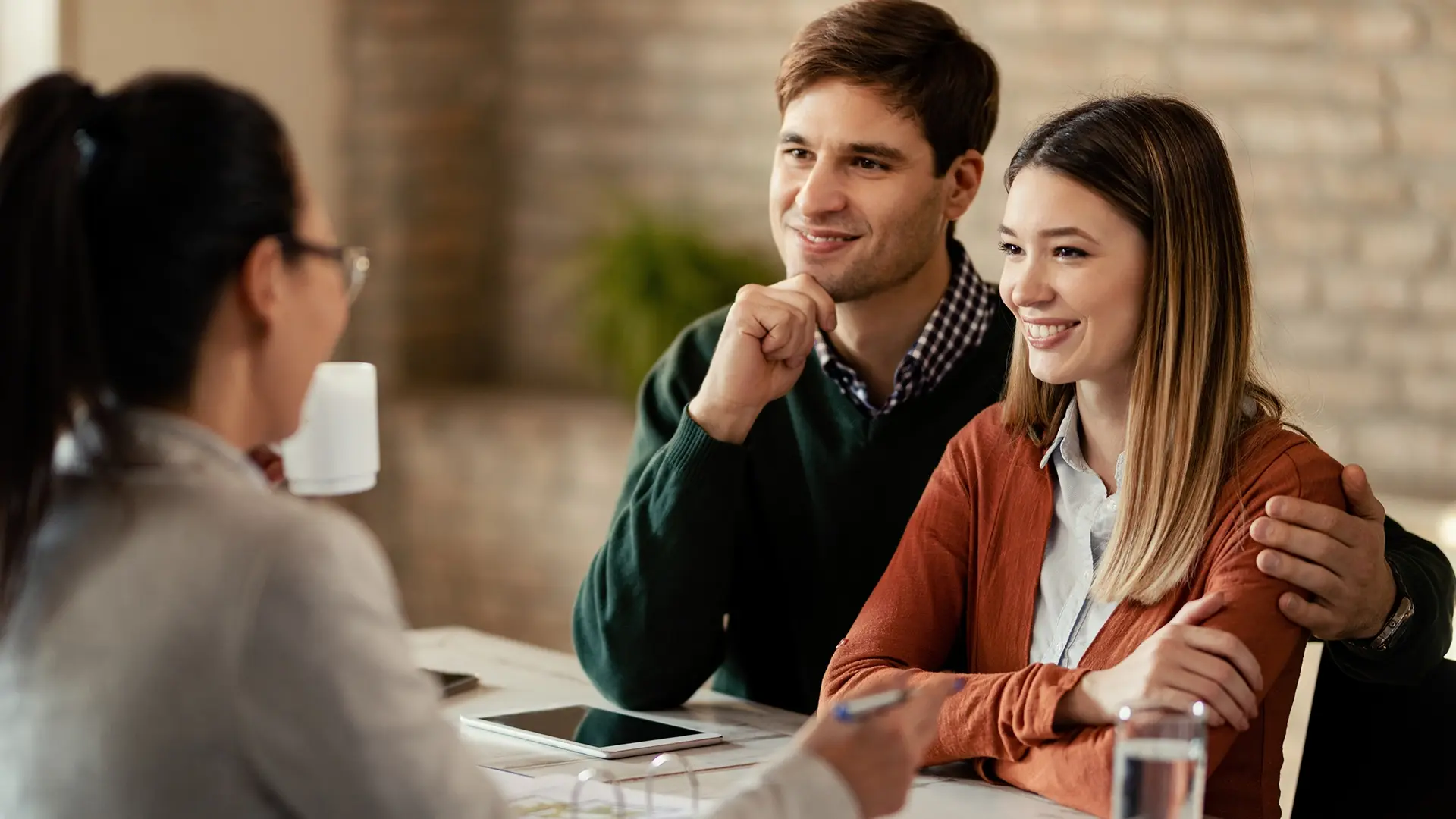 A smiling couple consults with a financial advisor, representing The Hartford’s commitment to providing personalized insurance and financial solutions