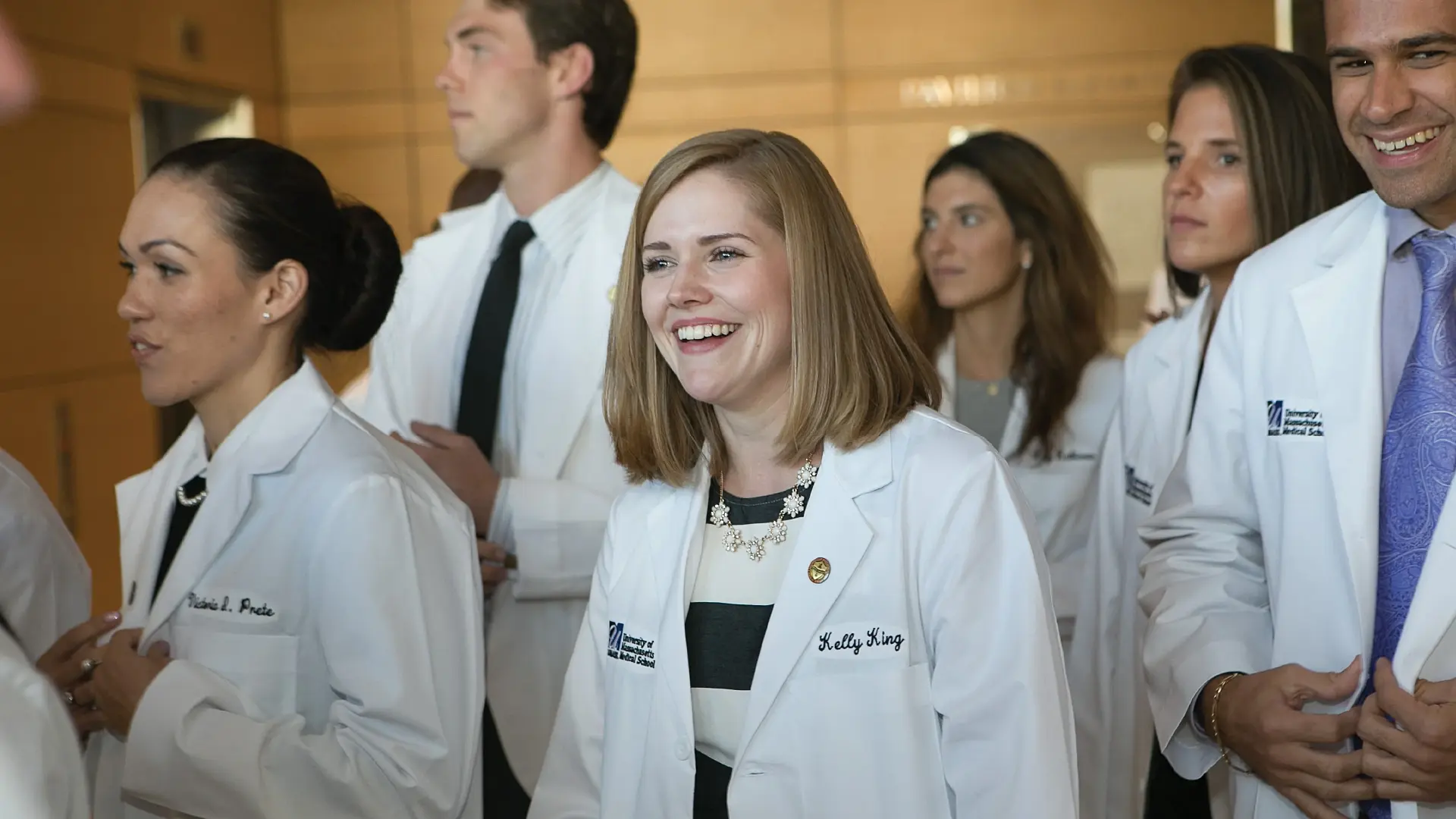  A group of smiling medical students in white coats at UMass Chan Medical School, symbolizing their dedication to healthcare and medical education