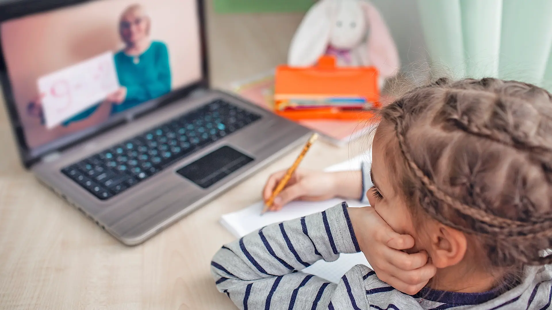  A young girl engages in an online class on her laptop, illustrating VIDIZMO’s role in supporting remote learning and digital education solutions