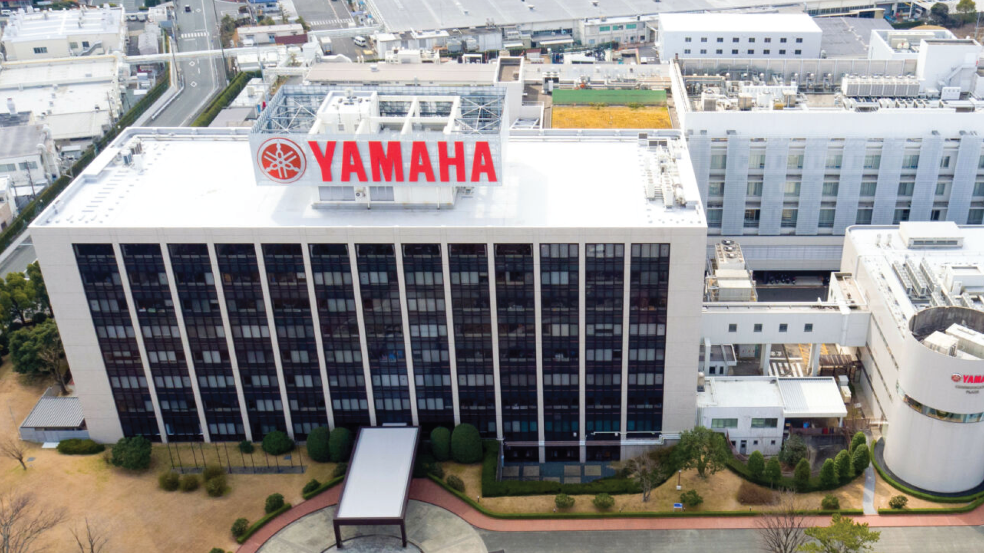 An aerial view of Yamaha's headquarters, showcasing the company's prominent building and logo, representing its global presence in manufacturing and innovation