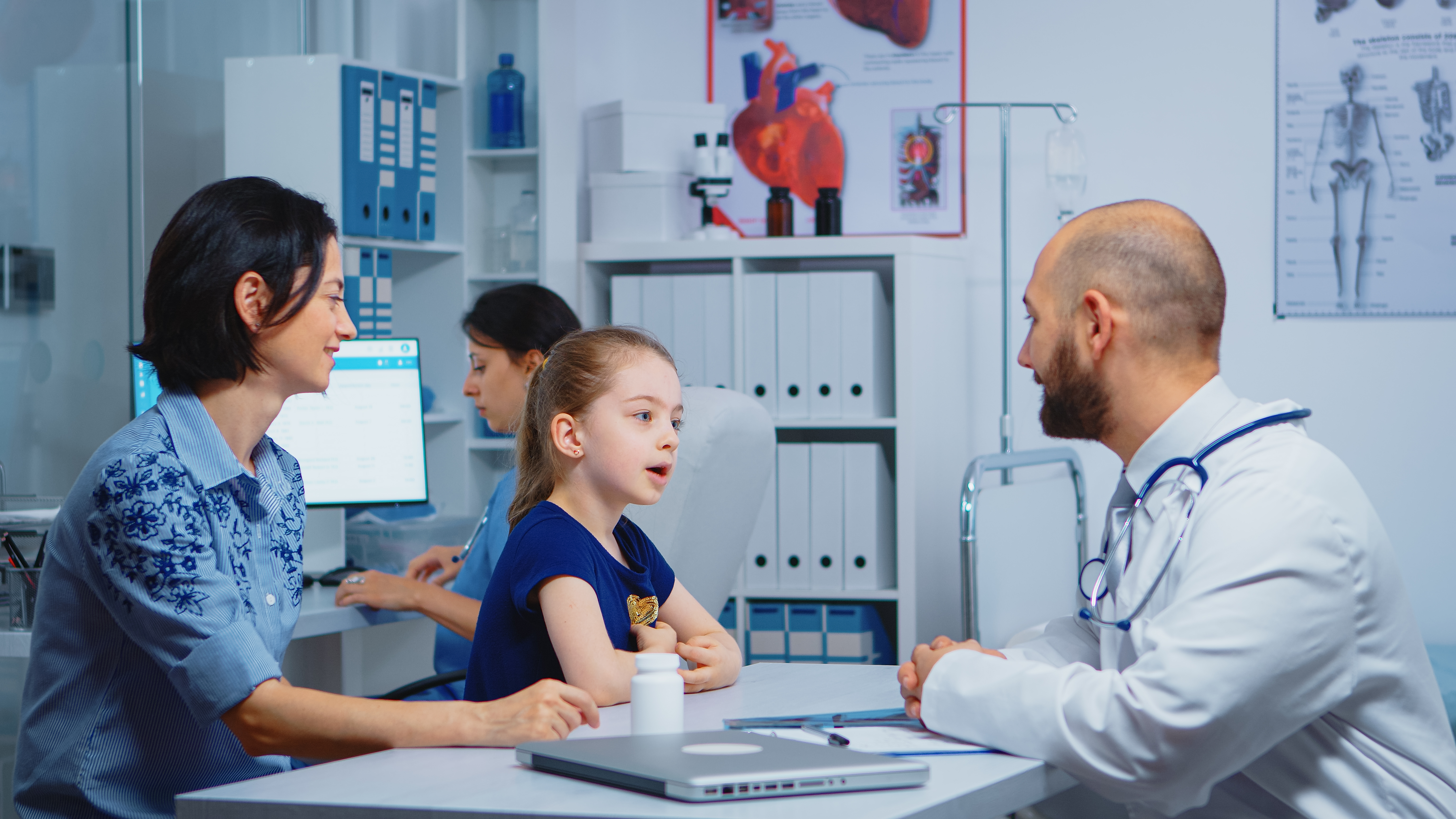 Pediatrician consulting with a child and parent during a clinical appointment